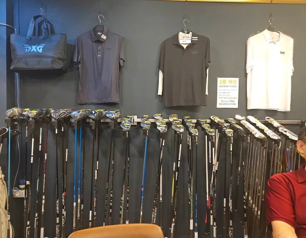 K GOLF샵의 드라이버 진열대와 위에 걸린 골프 셔츠, 2층 매장 안내판
